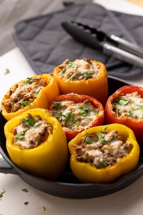Keto Stuffed Peppers in a cast iron pan with some tongs in the background